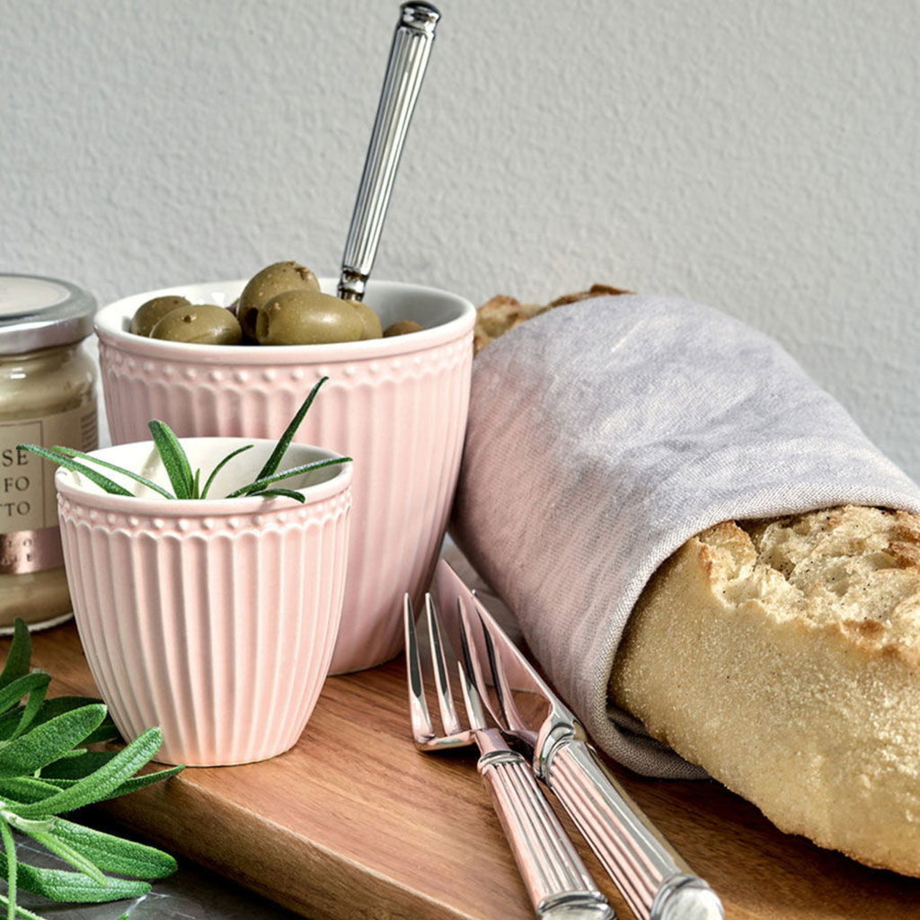 Silberbesteck von GreenGate auf einem Holzbrett mit Brot und Oliven, stilvoll arrangiert und hochwertig verarbeitet.